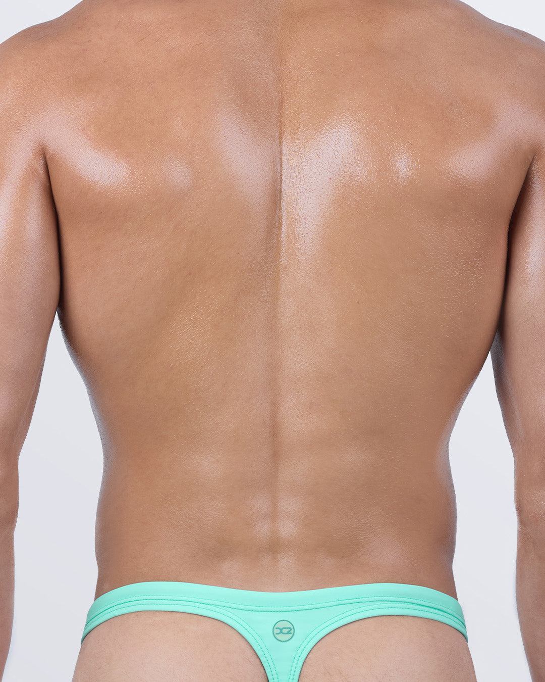 Back view of men’s swim thong in aqua green, showcasing the signature “T” back shape. Designed for a daring yet comfortable fit, it delivers perfect tan lines and a confident beach statement.