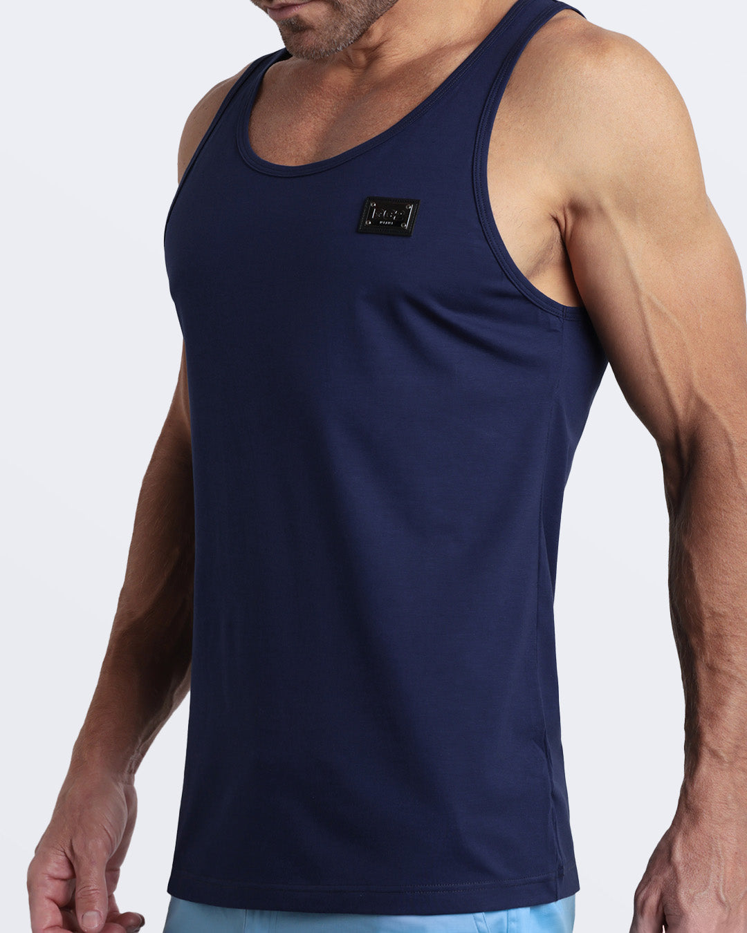 Side view of men’s workout tank top in BE MY NAVY a rich, deep navy blue color with a metallic plaque logo made by DC2 Clothing the new official brand of mens beachwear.