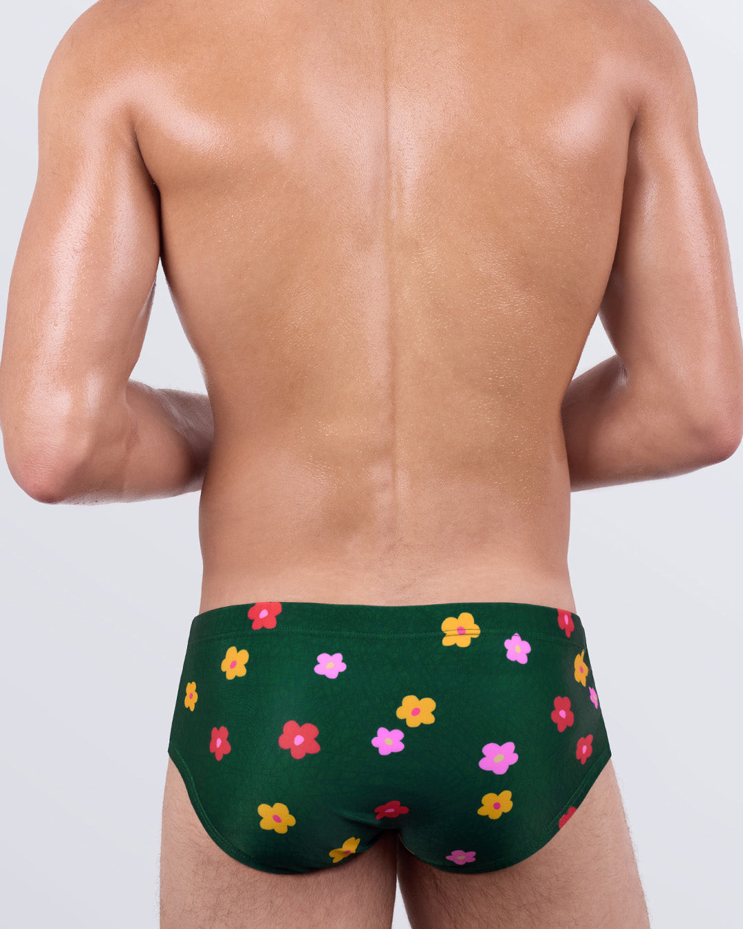Back view of BUY MYSELF FLOWERS Swim Sunga by DC2 Miami – men’s low-rise swimwear with multicolor flower pattern on green background and snug Brazilian fit.