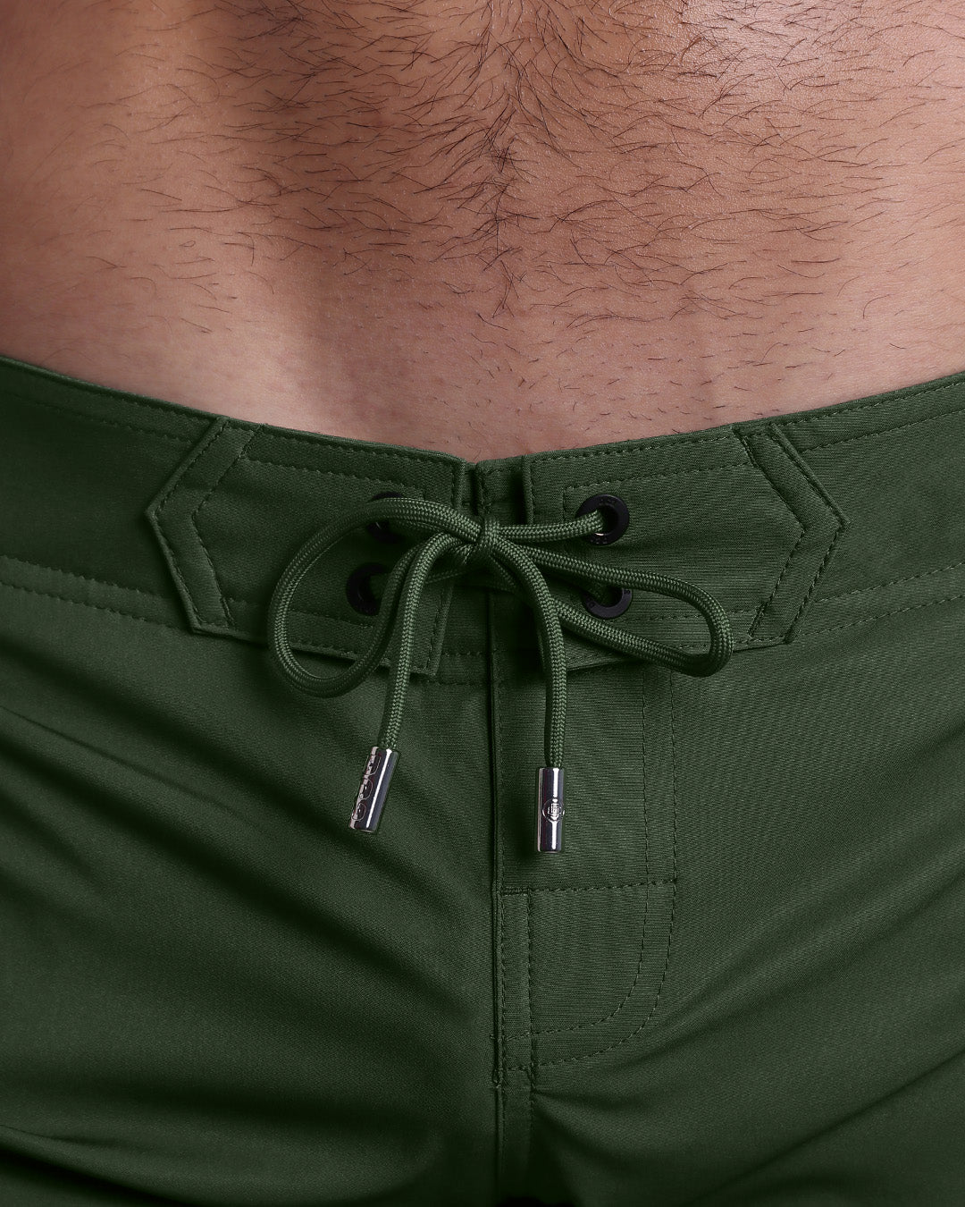 Close-up view of inseam and details of PALM GREEN beach shorts for men, with a green color cord and custom branded silver cord-ends, and matching custom eyelet trims in black.