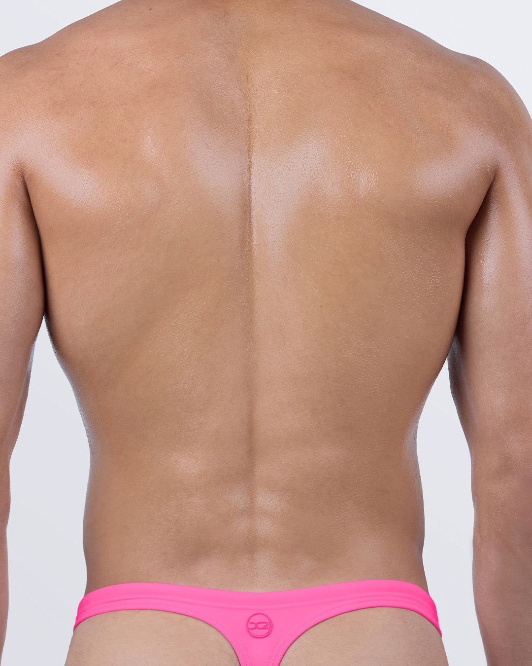 Back view of DC2 PINK BOMB swim thong for men, featuring a T-back design for ideal tan lines and ultra-light coverage.