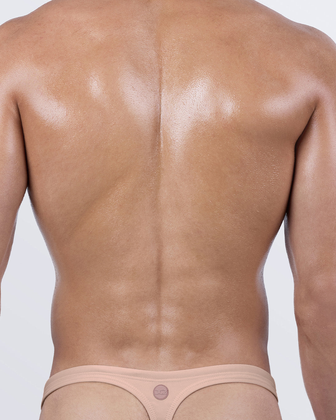 Back view of Skinny Dip Light Swim Thong by DC2 BANG — men’s thong swimsuit with T-back cut in tan nude tone