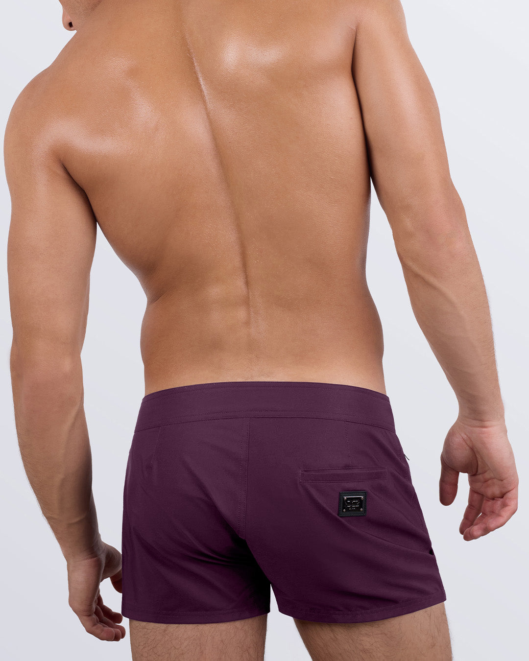 Back view of a male model wearing the men's VERY BERRY beach shorts by DC2 Miami a premium men's beachwear brand. Featuring a sleek fit and modern design, these versatile swimming trunks combine style and functionality for the perfect beach or poolside look.