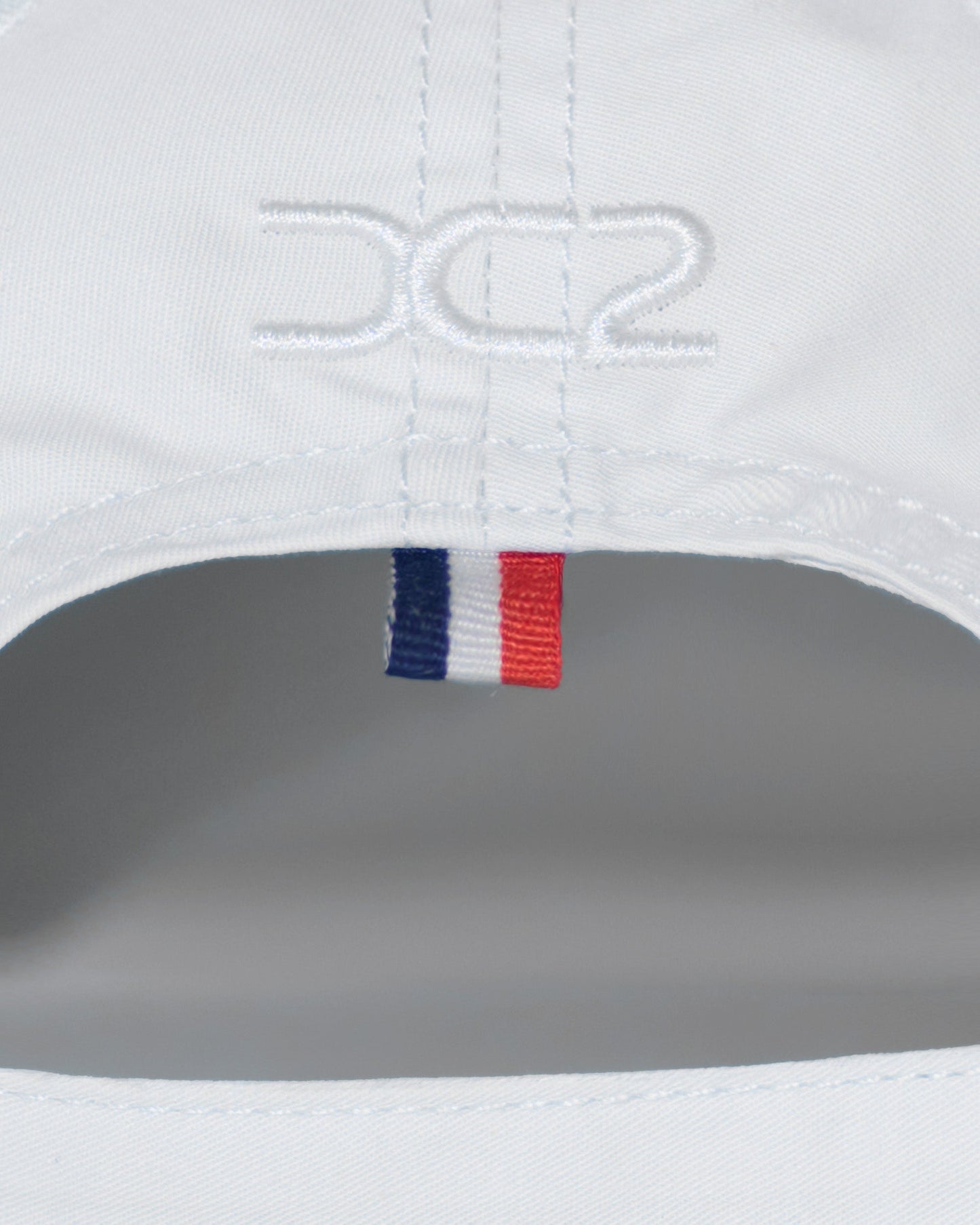 Back detail of the DC2 Resort Cap in White — featuring tonal stitching and a woven tricolor accent tab.