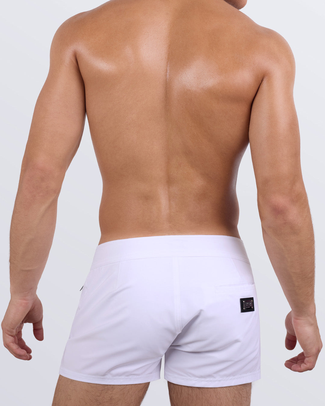Back view of a male model wearing the men's WHITE PARTY beach shorts by DC2 Miami a premium men's beachwear brand. Featuring a sleek fit and modern design, these versatile swim trunks combine style and functionality for the perfect beach or poolside look.
