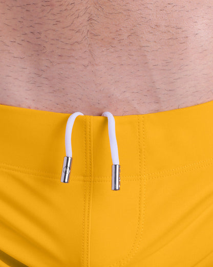 Close-up view of men’s summer beach shorts by DC2 clothing brand, showing white cord with custom branded metallic silver cord ends.