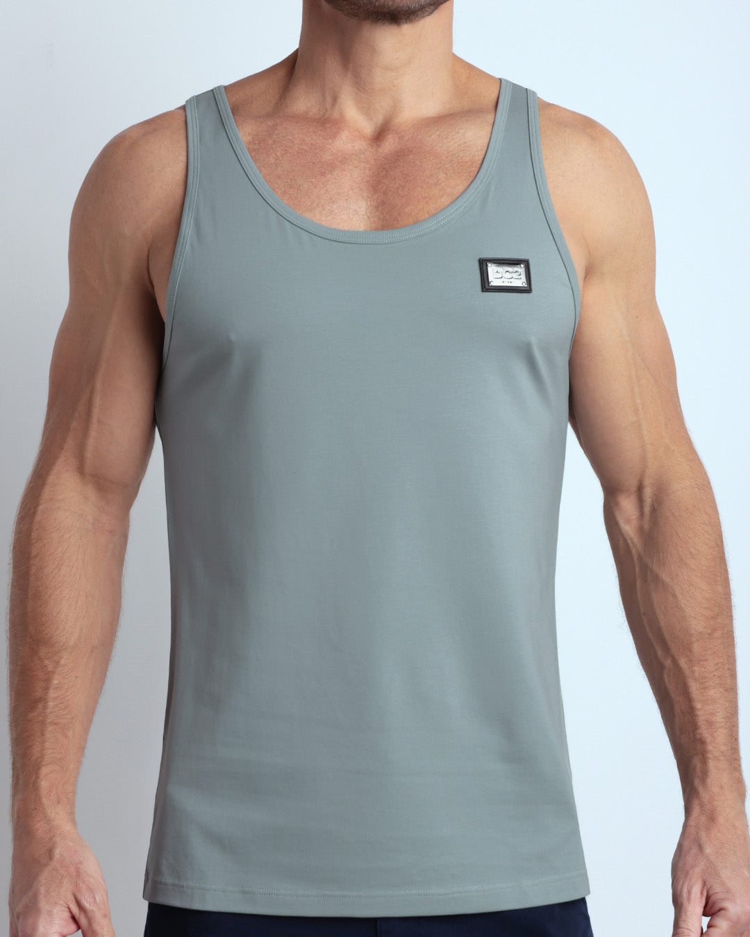 Frontal view of male model wearing the BARELY TEAL in a solid light teal color casual gym tank top for men by the DC2 brand of men's beachwear from Miami.