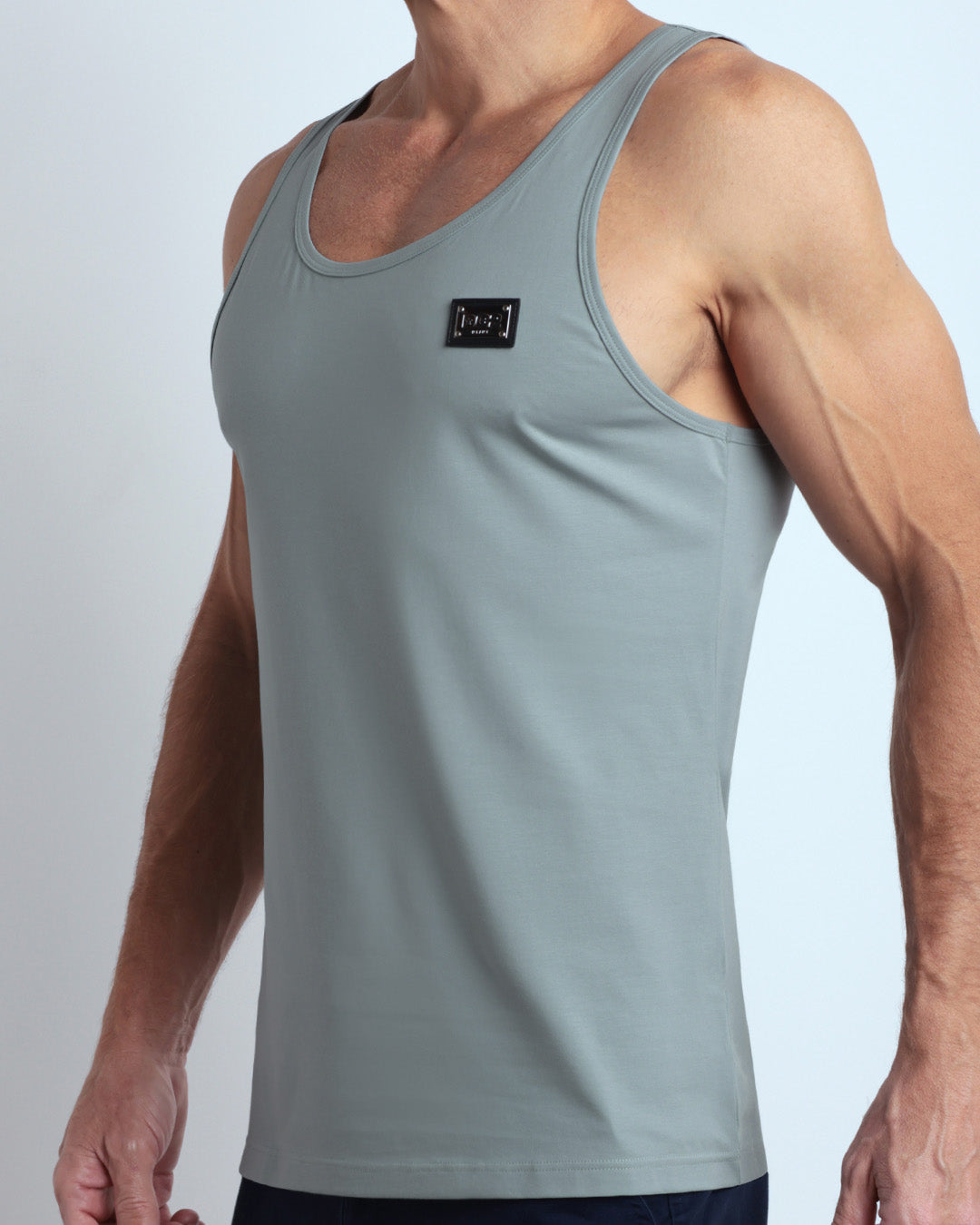 Side view of men’s workout tank top in BARELY TEAL a soft, muted teal shade color with a metallic plaque logo made by DC2 Clothing the new official brand of mens beachwear. 