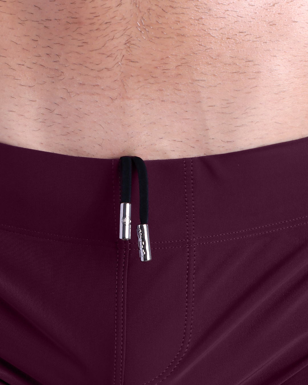 Close-up view of men’s summer beach shorts by DC2 clothing brand, showing black cord with custom branded metallic silver cord ends.