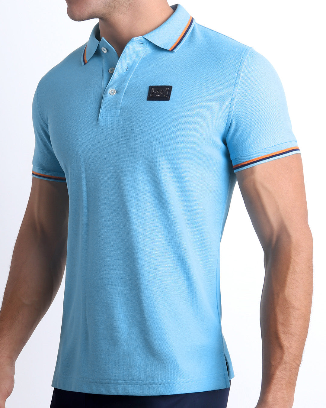 Male model wearing a slim-fitting, BISCAYNE LIGHT BLUE Pima Cotton Polo Shirt by Miami-based DC2. Solid light blue with orange and dark blue stripes on ribbed-knit collar and cuffs.