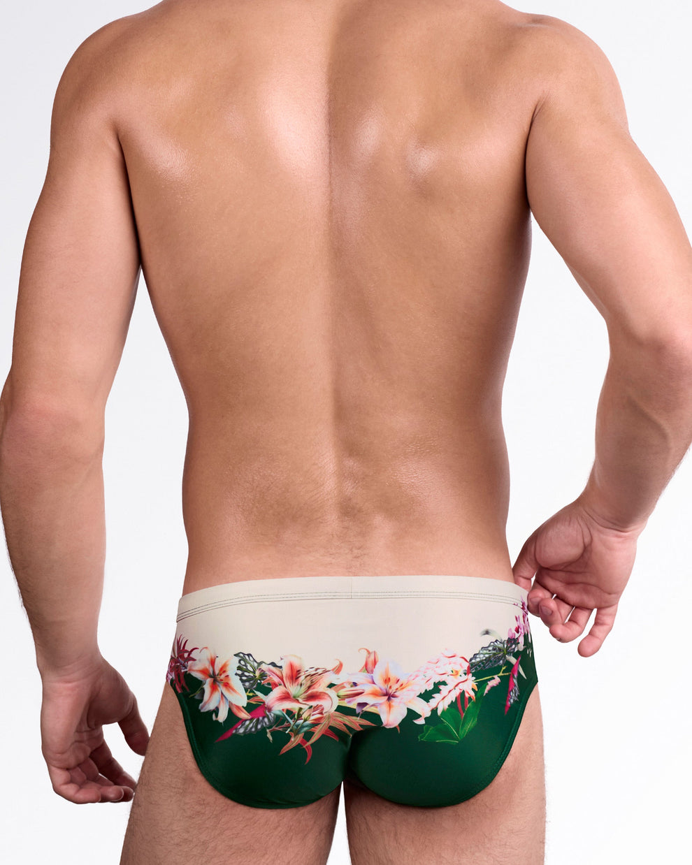 DC2 Bloom Service Swim Brief — back view showcasing wraparound botanical artwork with soft beige upper panel and rich green lower contrast.