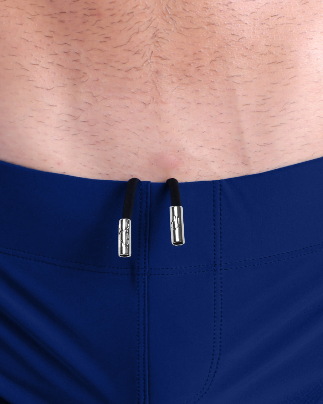 Close-up view of men’s summer beach shorts by DC2 clothing brand, showing black cord with custom branded metallic silver cord ends.