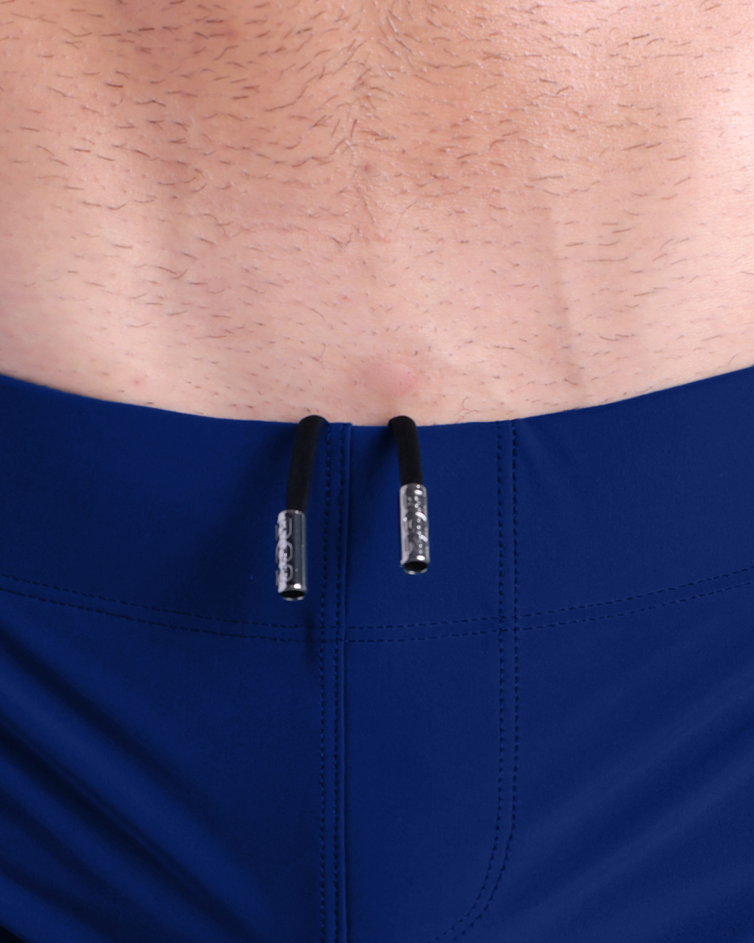 Close-up view of men’s summer beach shorts by DC2 clothing brand, showing black cord with custom branded metallic silver cord ends.