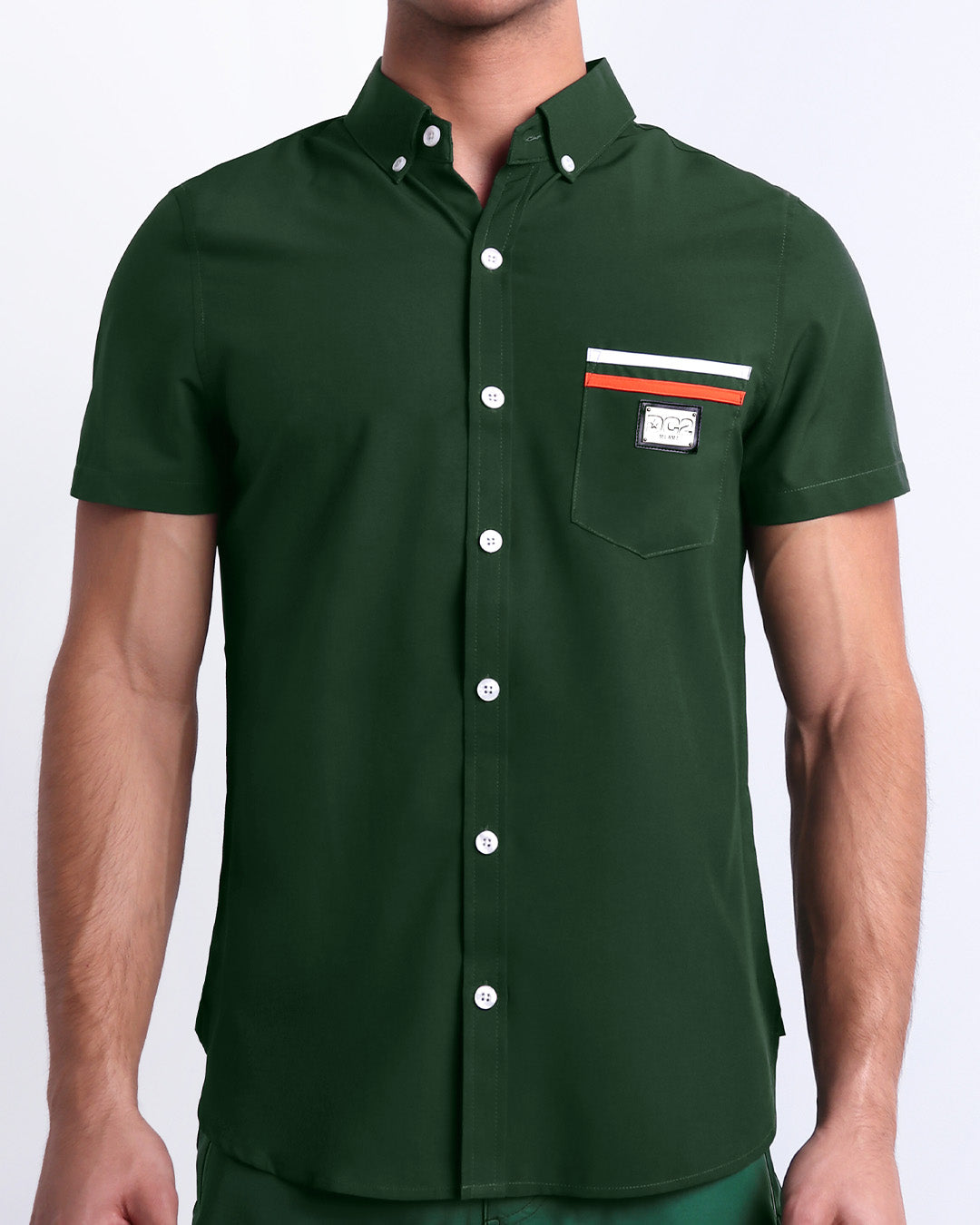 Male model wearing BRAVE GREEN men’s sleeveless stretch shirt. A premium quality top in a solid green color with orange and white stripes on the pocket, a men’s beachwear brand from Miami.