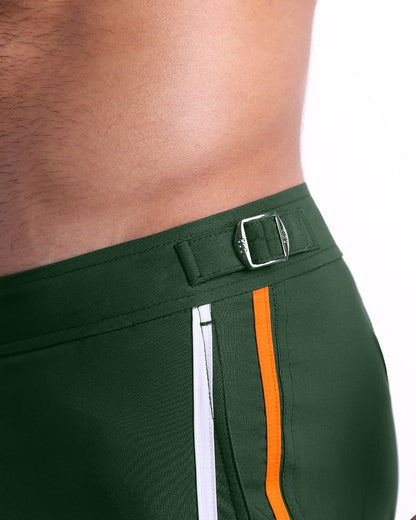 Close-up view of the BRAVE GREEN men’s swimwear, showing custom-branded silver adjustable side buckles.