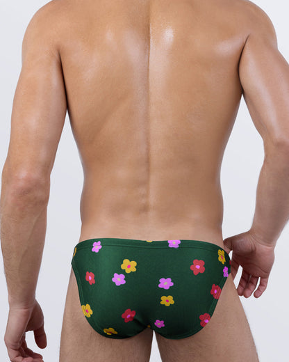 Back view of BUY MYSELF FLOWERS Swim Mini Briefs – men’s cheeky cut swimwear in dark green with pink, red, and yellow floral pattern, sculpted fit for tan lines.