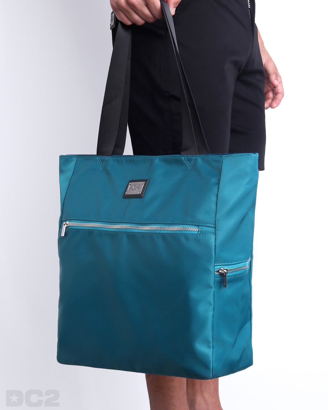 Side view of the CHIC TEAL Poolside Tote Bag Foldable/Portable by DC2 brand. Features smooth zipper in the front and the side, water resistant fabric, and the DC2 logo in a metallic silver plaque.