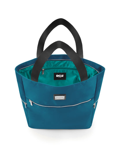 Top view of the CHIC TEAL Poolside Tote Bag by DC2 Miami, showcasing the spacious interior with a visible DC2 Miami logo label. The bag features a blue/green teal color with sturdy black handles and multiple zippered compartments for secure storage.