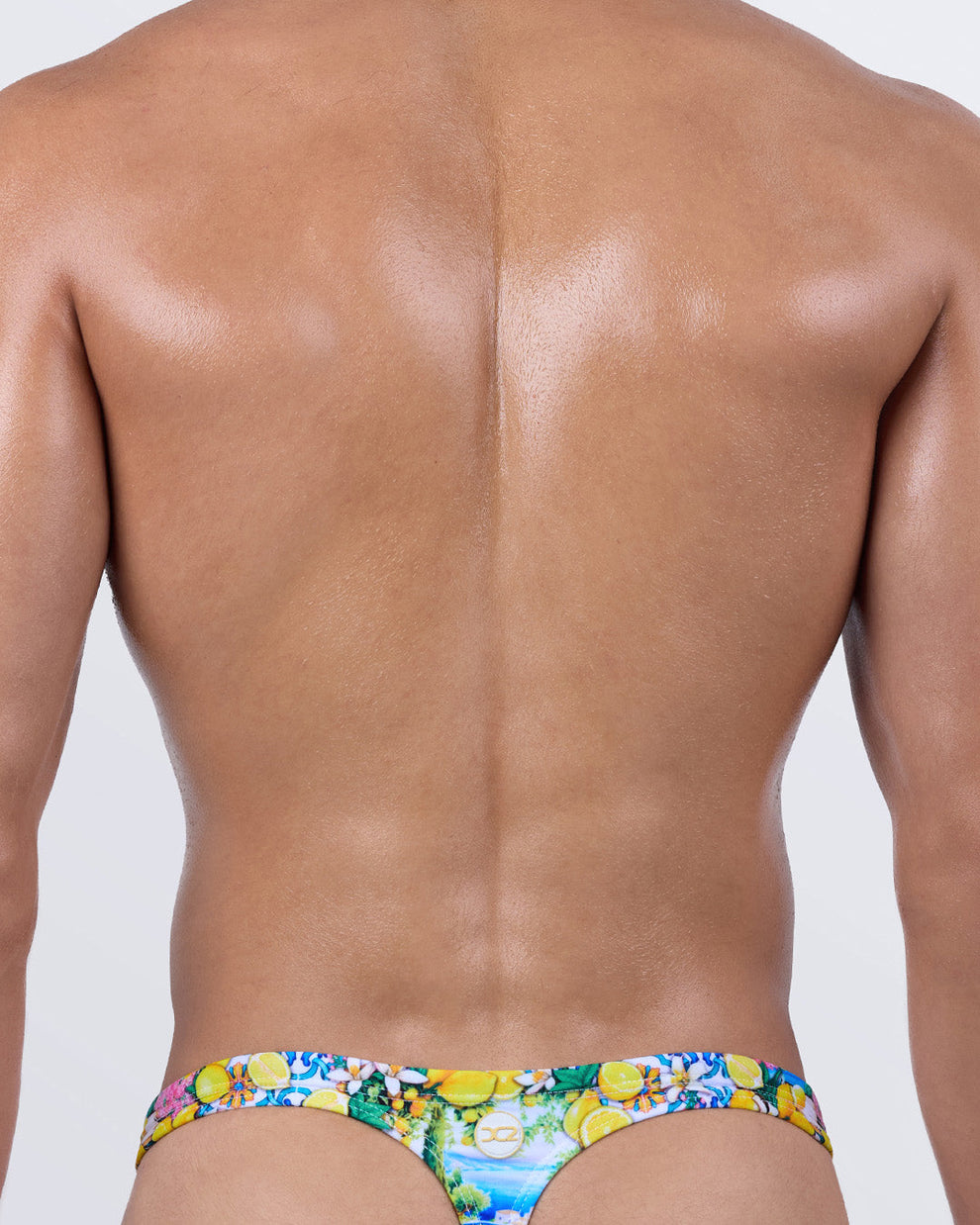 Back view of the men’s swim thong in CITRICS CHOICE by DC2 BANG! – T-back thong shape with colorful fruit and flower print, ideal for tanning and statement style.