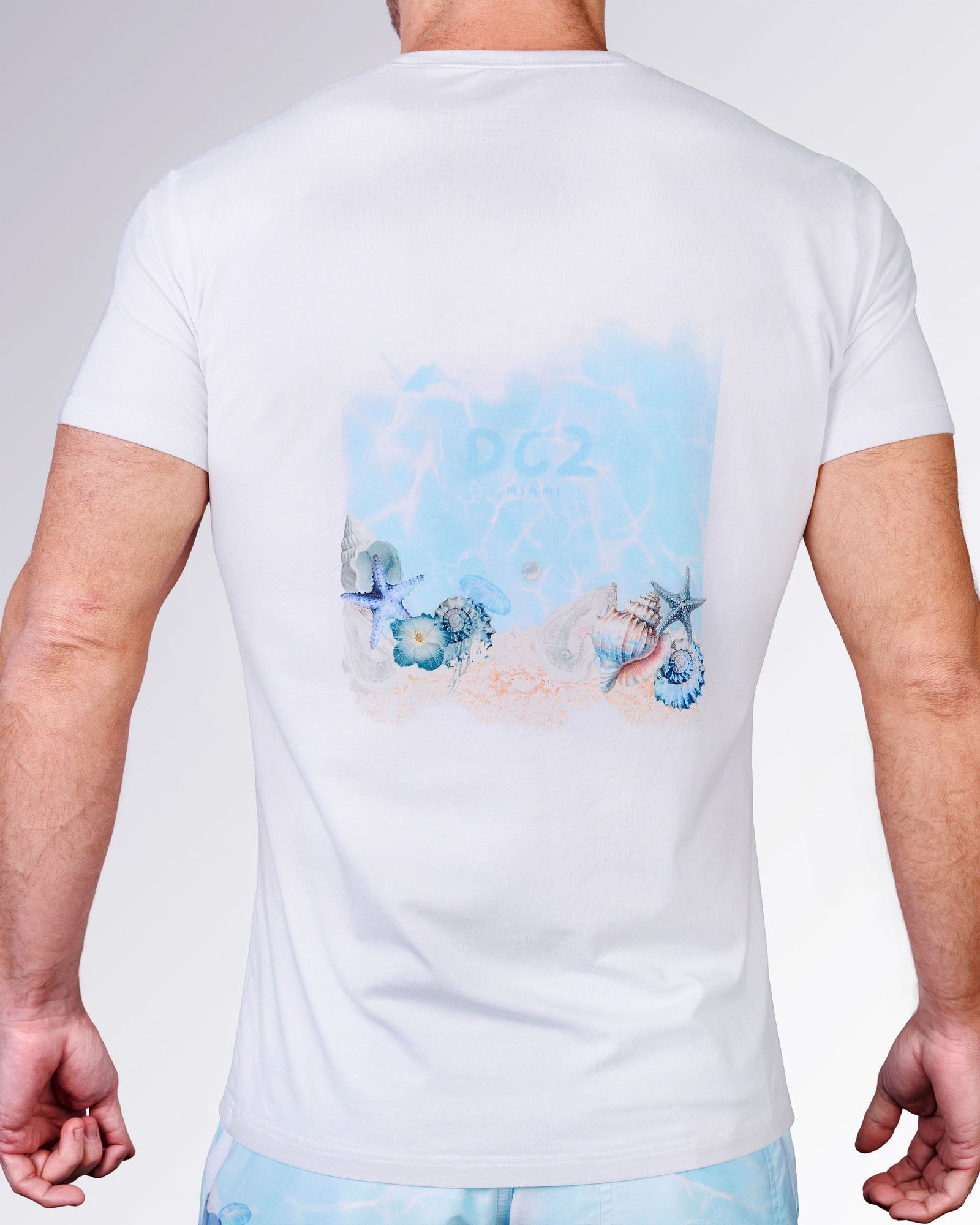 Close-up back view of the Coral Way Cotton Graphic T-Shirt by DC2 Miami, featuring pastel seashells, starfish and coral artwork.