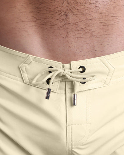 Close-up view of men’s summer Flex shorts by DC2 clothing brand, showing light yellow color cord with custom-branded golden cord ends, and matching custom eyelet trims in gold.