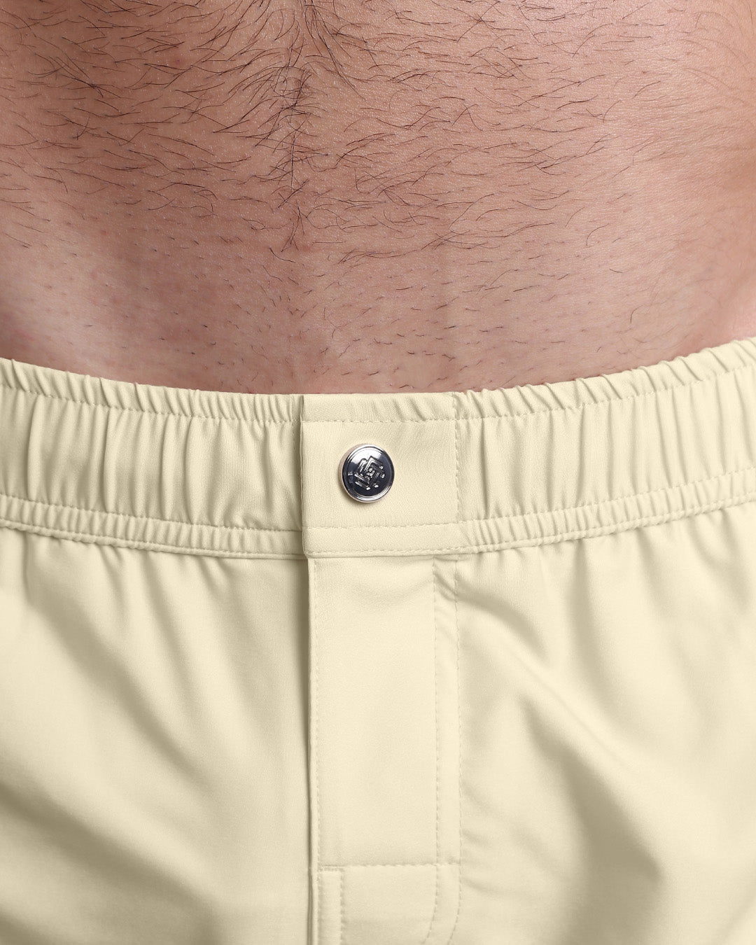 Close-up view of the men’s summer mini shorts, showing custom branded metal button in metallic silver.