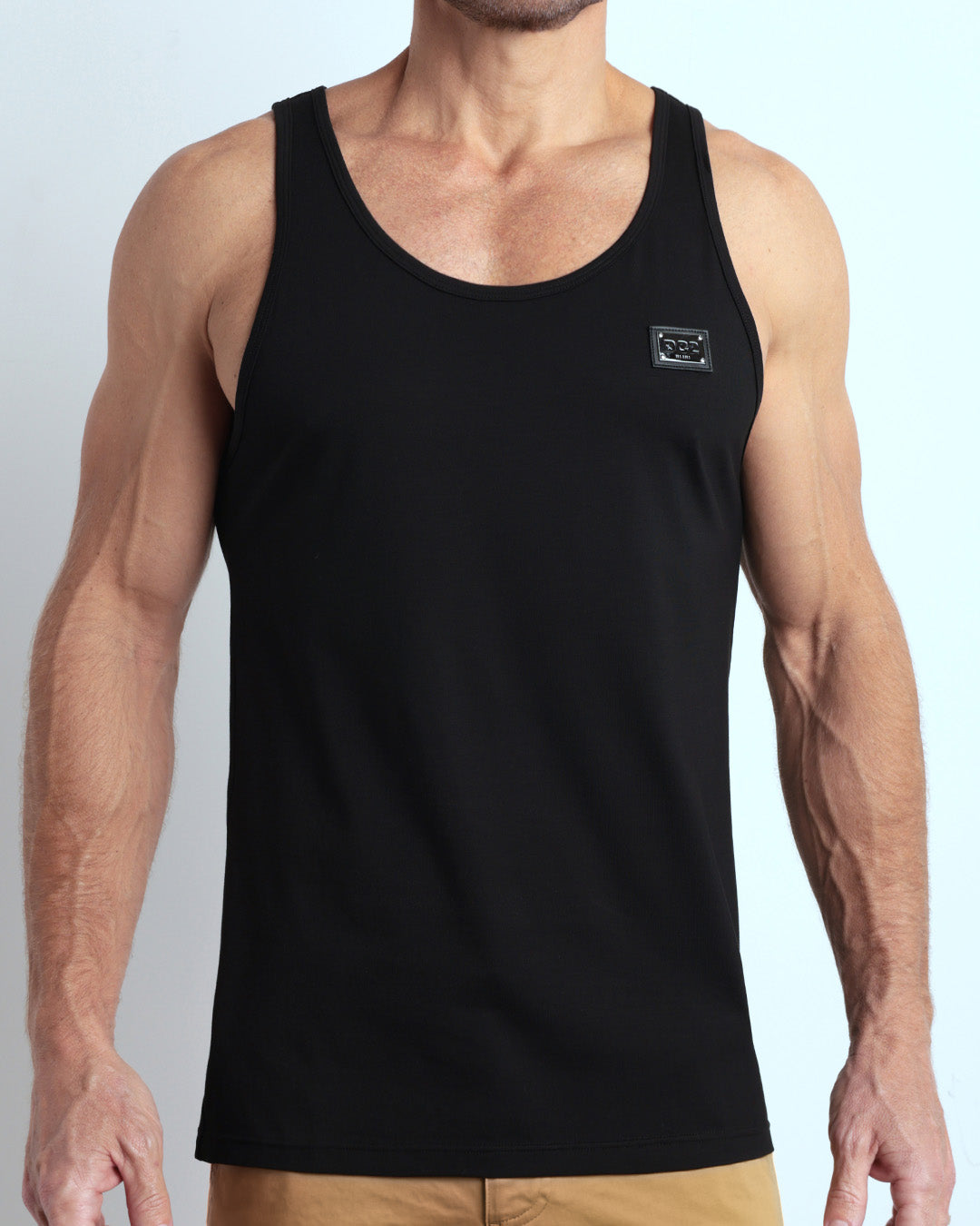 Frontal view of male model wearing the EXACT BLACK in a solid dark black color casual gym tank top for men by the DC2 brand of men's beachwear from Miami.