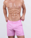 Model wearing FAST LINES (CHILL PINK) tailored shorts for men in soft pastel pink with a sleek, slim fit. Luxury men's swim trunks featuring adjustable side buckles and quick-dry premium fabric, perfect for beach days and resort wear.