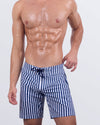 Frontal view of a male model wearing the FAST LINES (NAVY BLUE) Flex Boardshorts for men by DC2 Miami. These stylish above-the-knee boardshorts feature a classic navy blue and white vertical stripe pattern, a hybrid waistband with a flat front and elasticated back, and a secure lace-up closure, perfect for beach days and water sports.