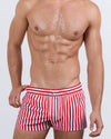 Frontal view of a masculine model wearing the FAST LINES (RAPID RED) Mini Shorts for men by DC2 Miami, a premium swimwear brand. These ultra-short beach shorts feature bold red and white vertical stripes, an elastic waistband with an adjustable internal drawstring, and a sleek fitted cut, making them perfect for summer vibes, beach days, and poolside lounging.
