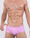 Model wearing FAST LINES (CHILL PINK) Swim Sunga – front view. Featuring vertical pastel pink and white stripes in a Brazilian-inspired silhouette that sits mid-rise on the waist for a flattering and secure fit.