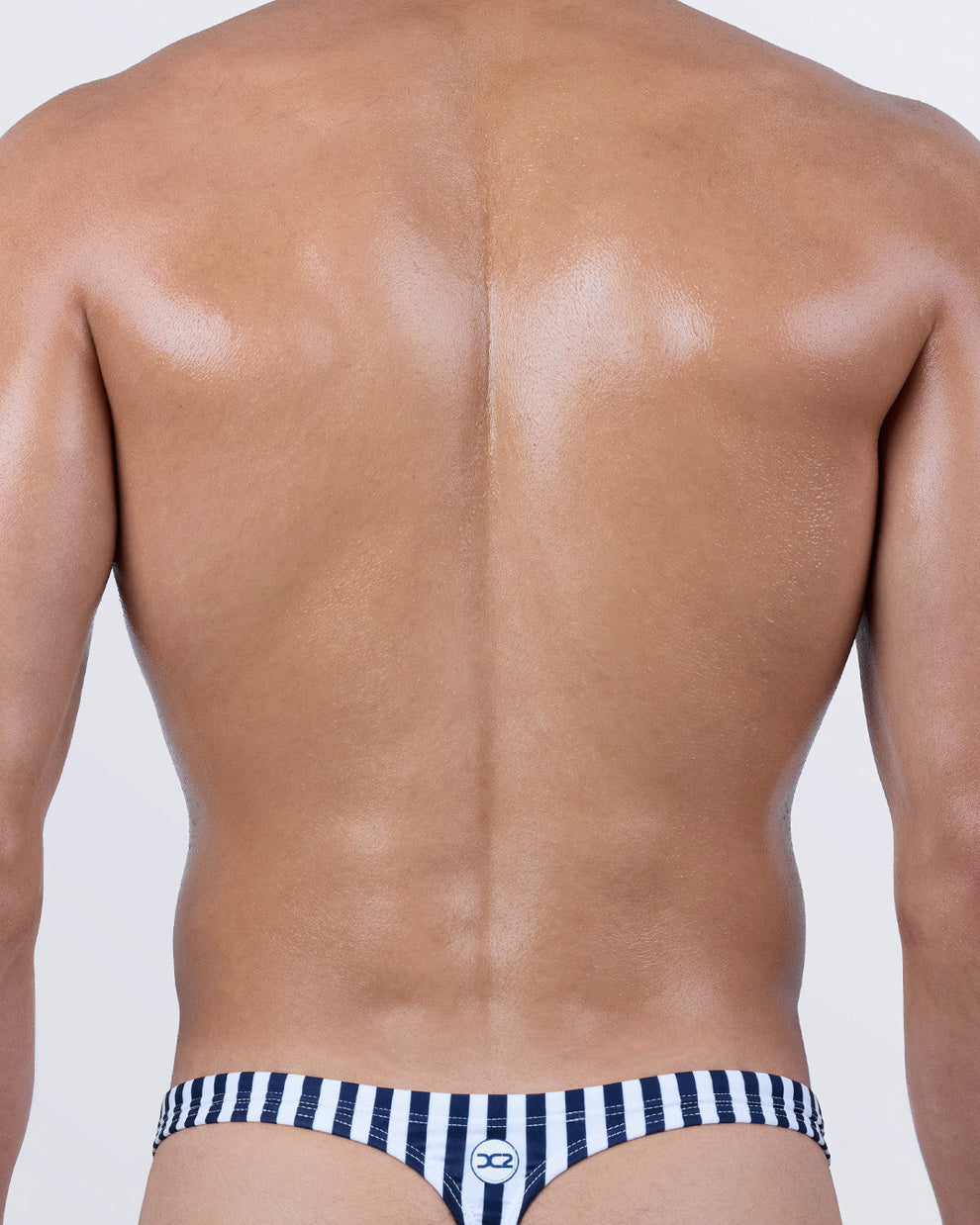 Back view of the FAST LINES (NAVY BLUE) swim thong with signature “T” back shape for perfect tan lines. Clean vertical stripes and snug waistband deliver a bold yet refined look from behind.
