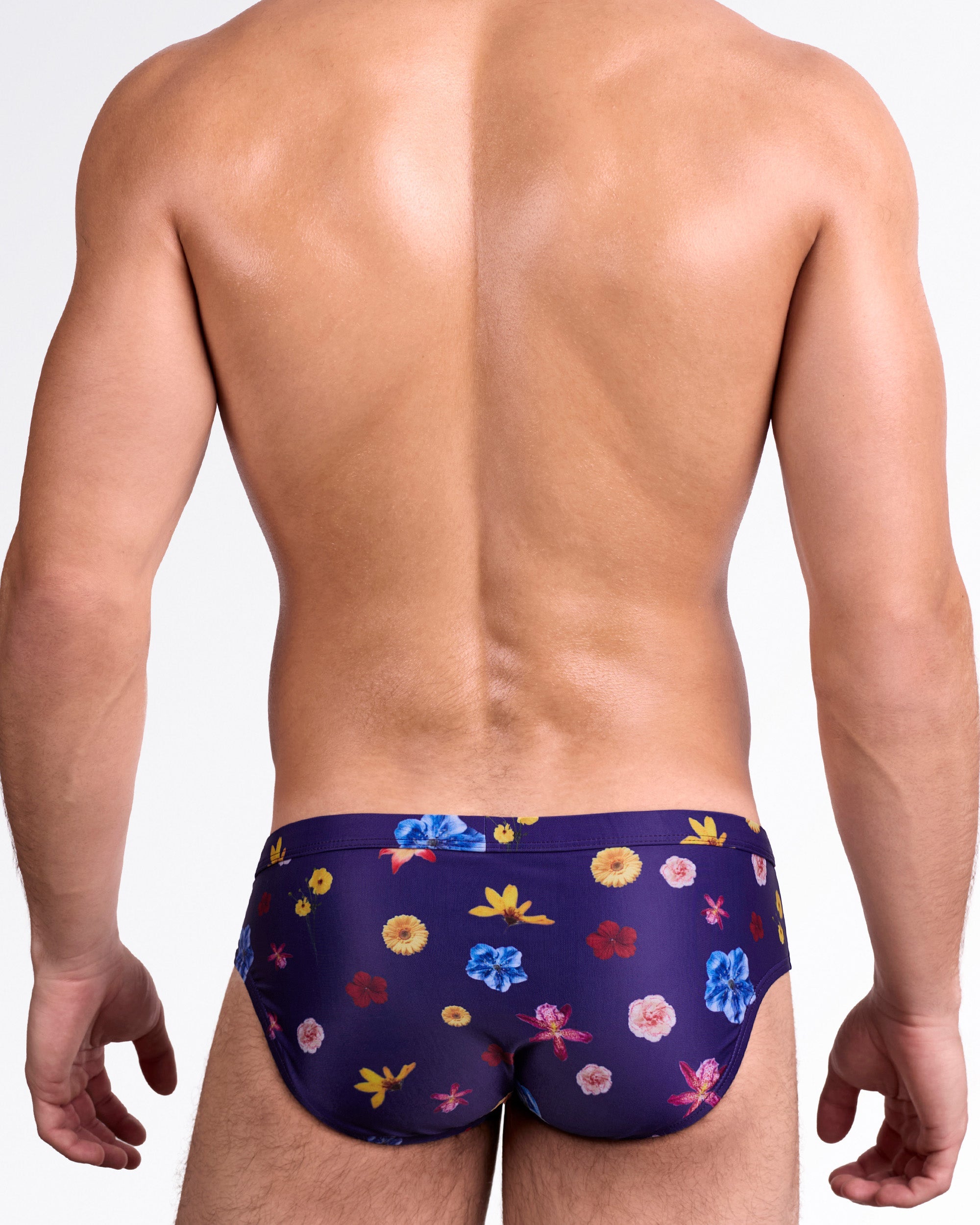 DC2 Flower Powers Blue Swim Brief — back view highlighting full-coverage rear with vibrant red, yellow, pink, and blue flower pattern on rich navy background.