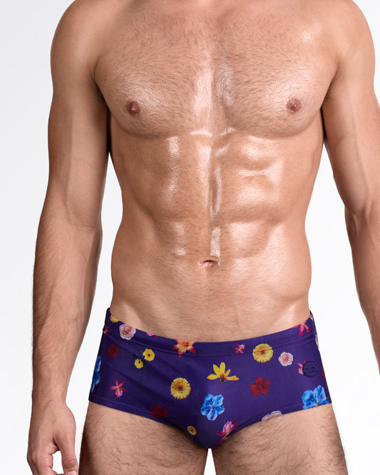 DC2 Flower Powers (Blue) — model wearing Flower Powers Blue Swim Sunga featuring a rich indigo base with scattered multicolor floral prints and a sleek, sculpted sunga silhouette.