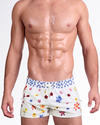 DC2 Flower Powers (Cream) Poolside Shorts — model wearing cream-colored poolside swim shorts featuring a vibrant scattered floral print, adjustable drawstring waistband, and modern short-length beach silhouette.