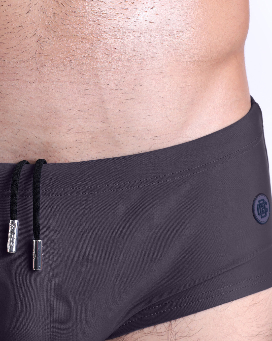 Close-up view of the GOTAHM GREY men’s drawstring briefs showing white cord with custom branded metallic silver cord ends, and matching custom eyelet trims in silver.