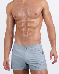 Frontal view of a sexy male model wearing sleek gray men's beach shorts by DC2 Miami, a premium swimwear brand. Designed for style and comfort, these modern-fit swim shorts offer a tailored look perfect for beach days, poolside lounging, and summer adventures.