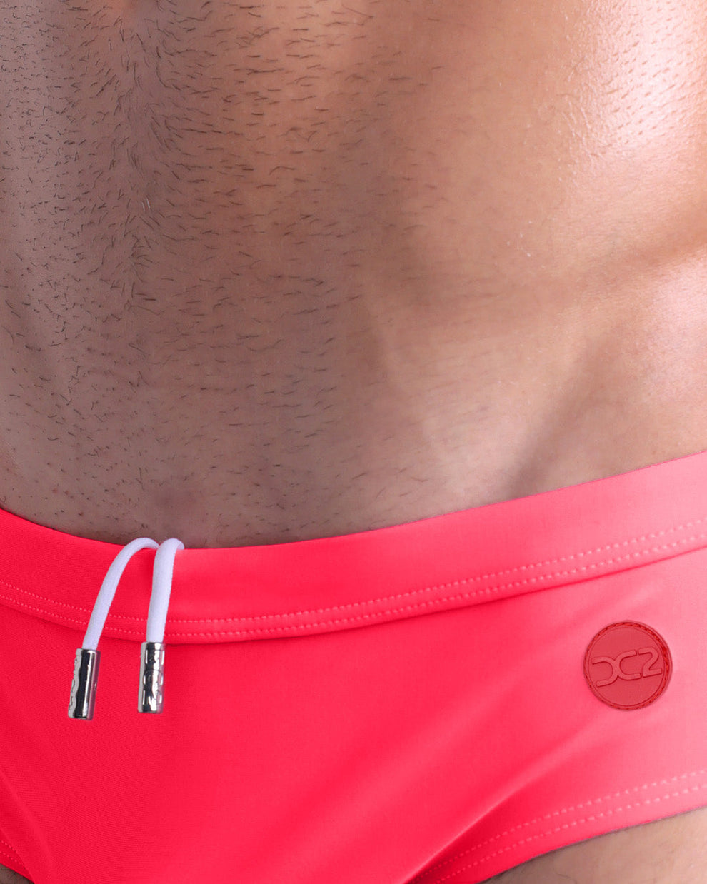 Close-up detail of HIGH VOLTAGE RED Swim Briefs — adjustable drawcord and DC2 rubber logo.
