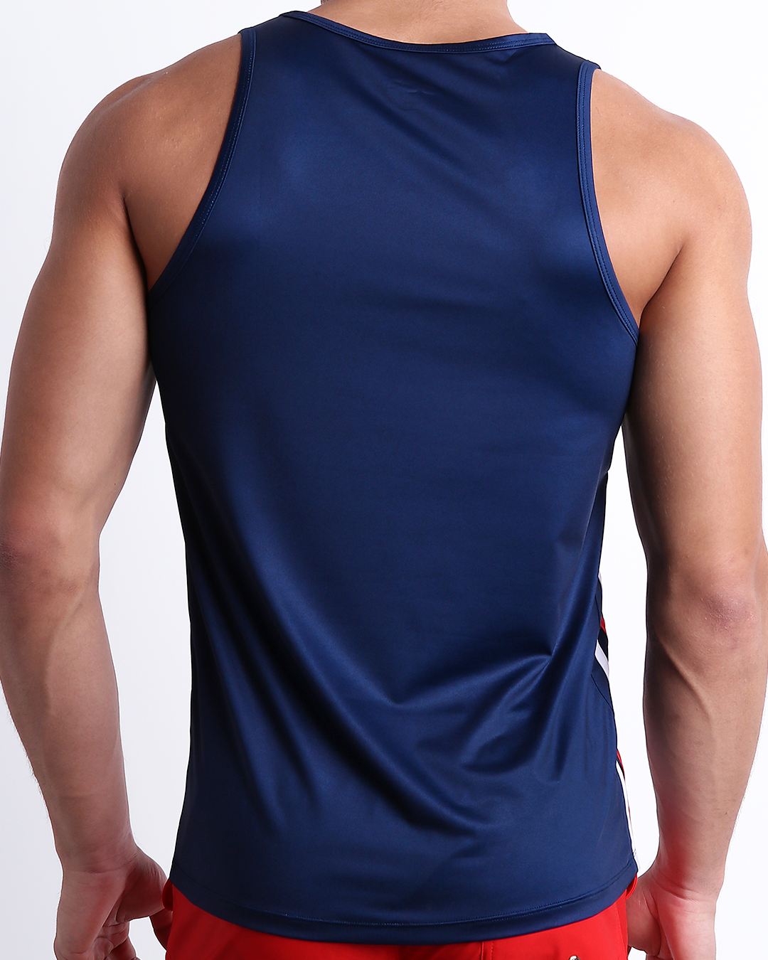 Male model wearing men’s IMPERIAL BLUE men’s Summer Tank Top in dark blue color with stylish white and red colored stripes. This high-quality shirt is by DC2, a men’s beachwear brand from Miami.