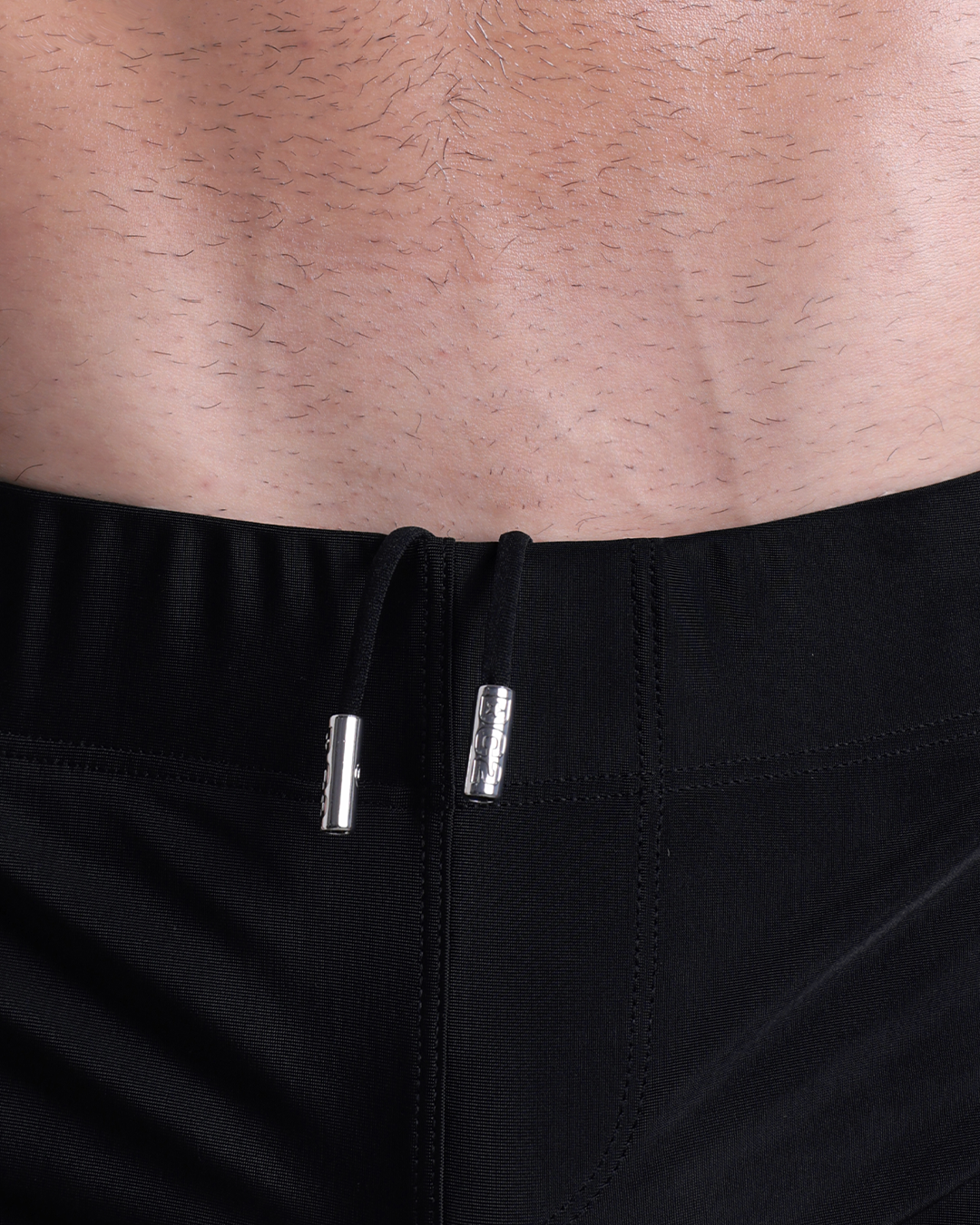 Close-up view of men’s summer beach shorts by DC2 clothing brand, showing black cord with custom branded metallic silver cord ends.