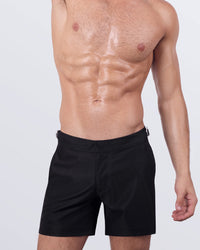 Male model wearing JET BLACK swimming Tailored Shorts, in a dark black color for men. These premium quality swimwear bottoms are by DC2 by BANG! Clothes, a men’s beachwear brand from Miami.