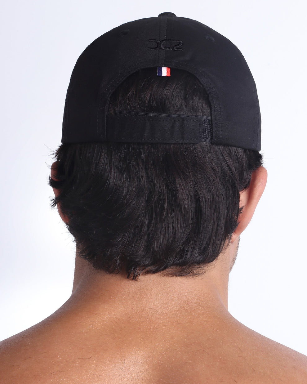 Back view of DC2 black resort cap, adjustable strap closure with a sleek, understated finish.