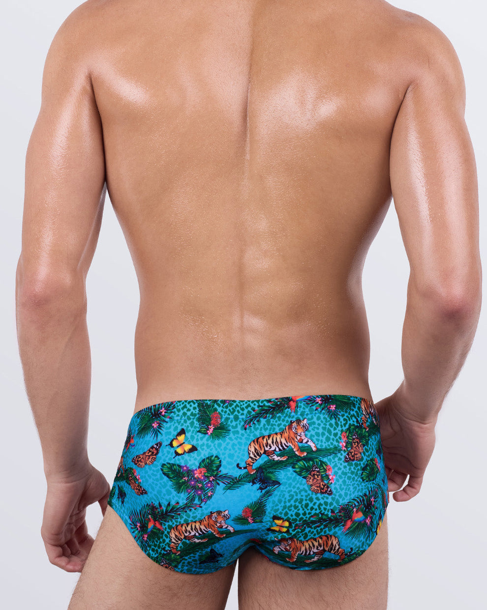Back view of Jungle Boogie men's swim sunga – bold luxury swimwear with tropical wildlife print, tigers and butterflies over aqua blue backdrop – DC2 Miami beachwear.