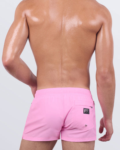 Back view of LA BEACH EN ROSE men’s poolside shorts showing soft-stretch fabric, elastic waistband, and a flattering quad-hugging silhouette in a bold rose-pink hue.