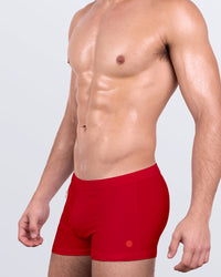 DC2 MAJESTIC RED Swim Trunks — model wearing men’s swim trunks in bold red, featuring square-cut silhouette and fitted design.