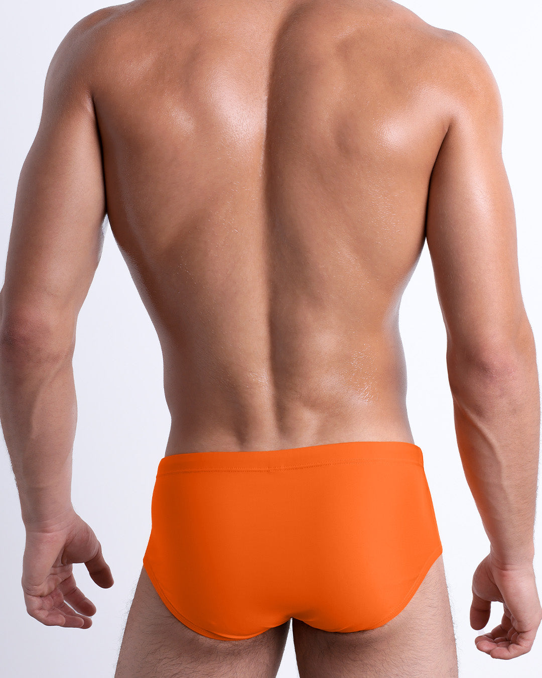 Back view of a male model wearing the MATCH POINT ORANGE beach Brazilian Sunga swimwear for men by BANG! Miami in a solid bright orange color.