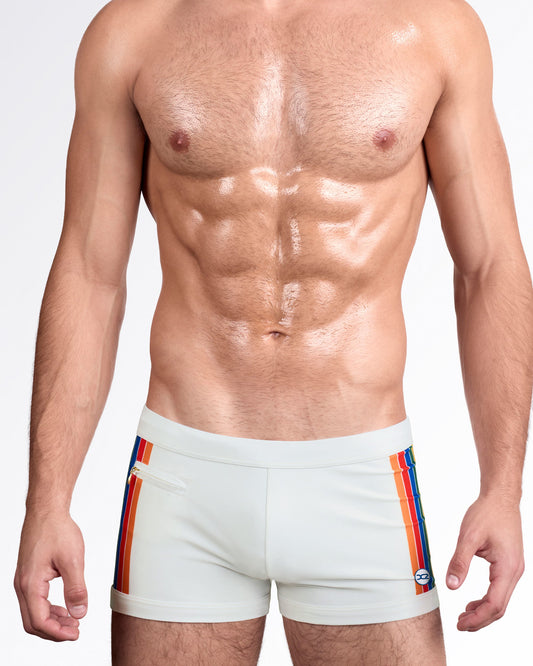 DC2 Mixtape Stripes — model wearing Mixtape Stripes Swim Trunks in soft sand featuring vertical multicolor racing stripes and tailored silhouette.