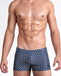 DC2 Mono Waves (Blue) — model wearing Mono Waves Blue Swim Trunk featuring a deep navy base with a geometric wave-inspired circular pattern in crisp white throughout.