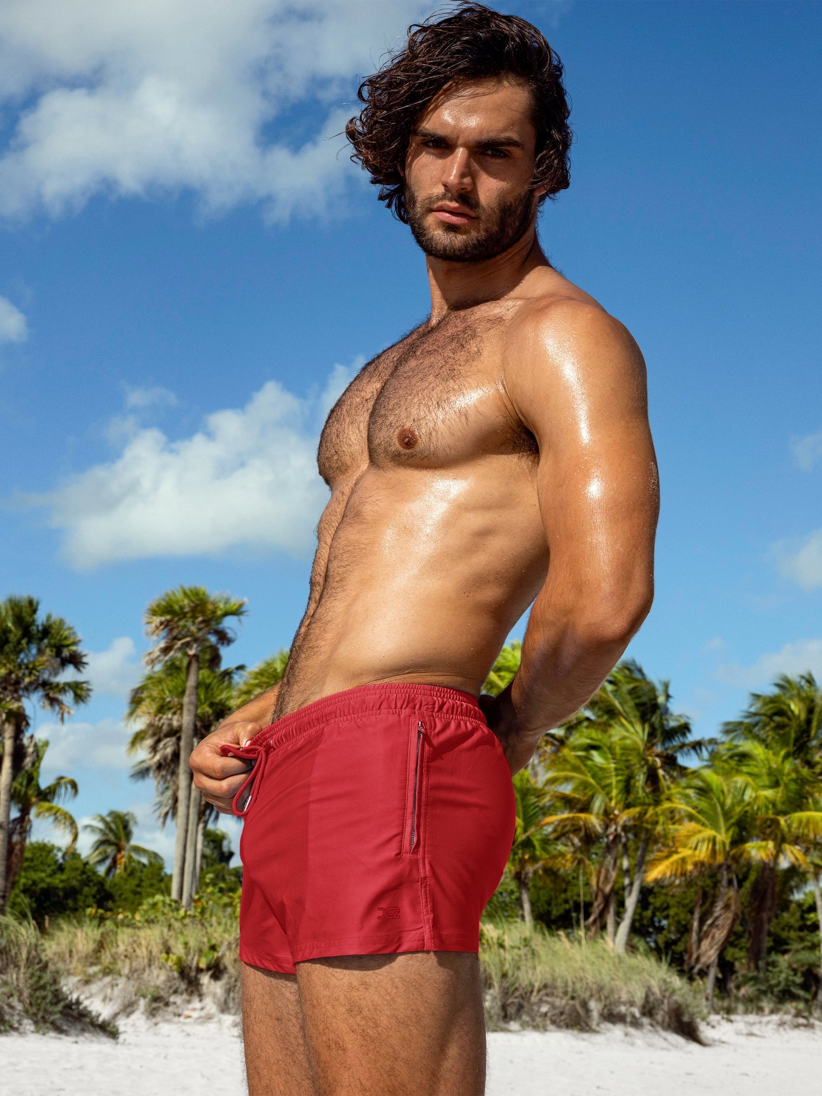 Model wearing Majestic Red Poolside Shorts in a bold solid red colorway with a lightweight fit, side zip pocket and clean, modern swim silhouette.