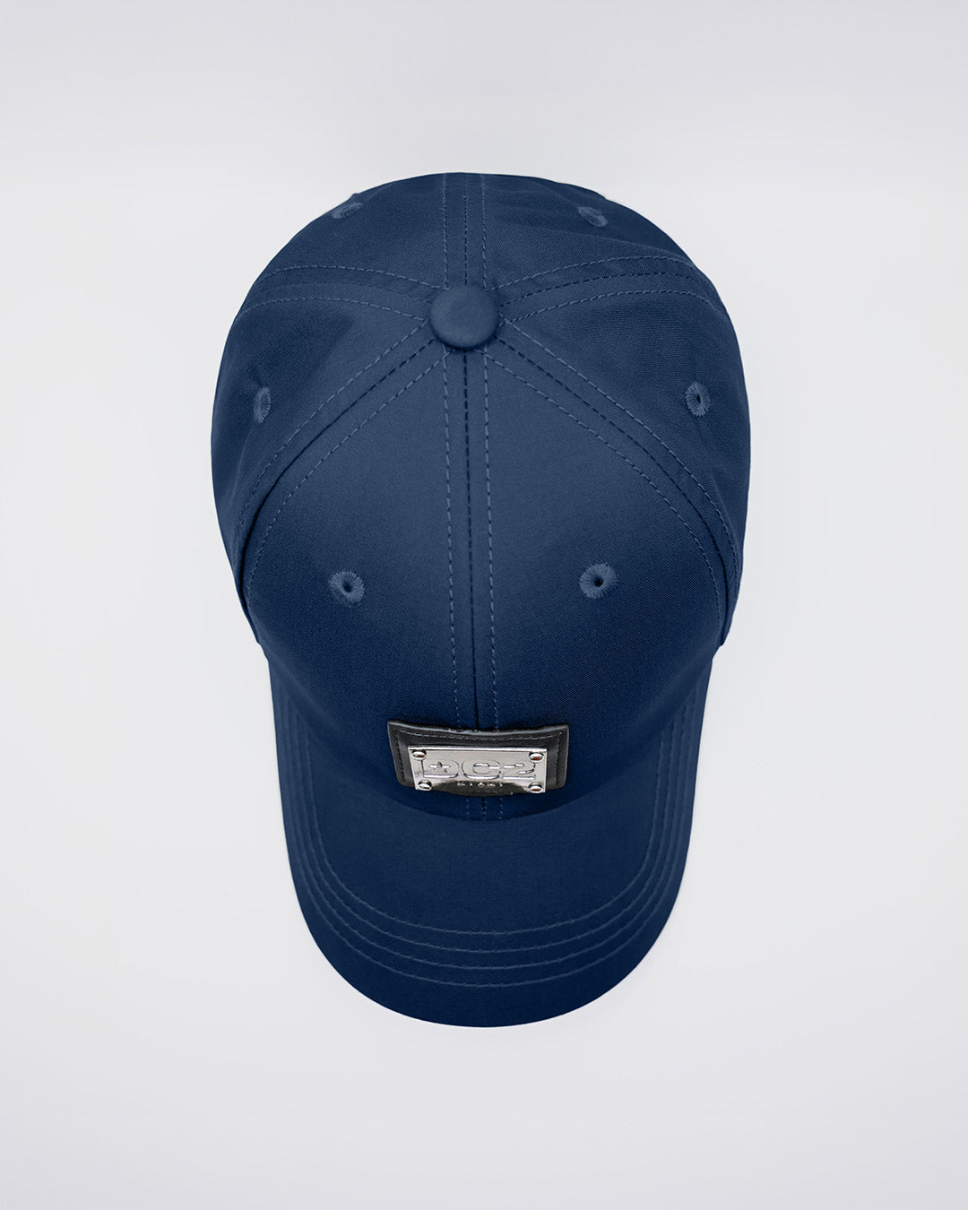 Close-up of a NAVY BLUE Baseball Cap with polished DC2 metallic silver plaque. Features ventilation eyelets on the cap to provide extra breathability, perfect for active wear.